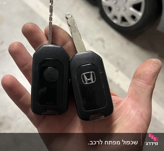מפתחות רכב ביד על רקע חניה